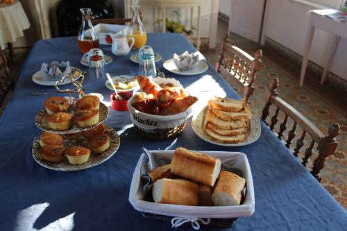 a blue table topped with plates of bread and pastries at Ferme Du Pre Vert - Chambres d'hôtes B&B in Nort-Leulinghem