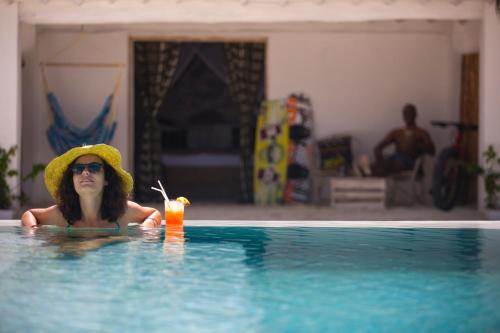 a woman wearing a hat and a drink in a swimming pool at The Loop Beach Resort in Jambiani