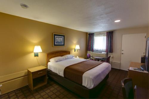 a hotel room with a large bed and a television at EastGate Inn in Littleton