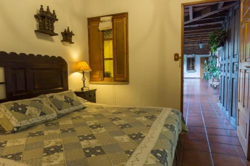 1 dormitorio con 1 cama y pasillo con suelo en Hostal San Nicolas, en Antigua Guatemala