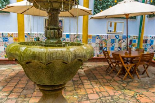 una fontana in un cortile con tavolo e ombrelloni di La Mansion Hostel a San Gil