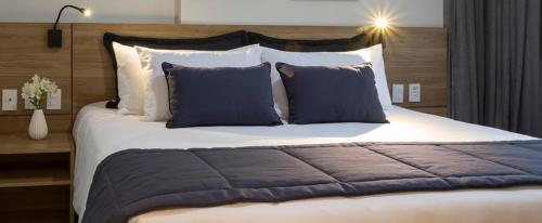 a bedroom with a large bed with blue and white pillows at Flat Mangabeiras e manacás Granja Brasil Itaipava in Itaipava