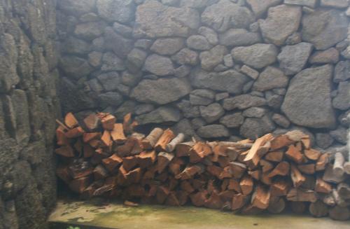 a pile of wood piled against a stone wall at Yes Pico in Santa Luzia