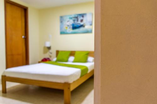a bedroom with a bed with green pillows at Sam'S VIP Hostel San Gil in San Gil