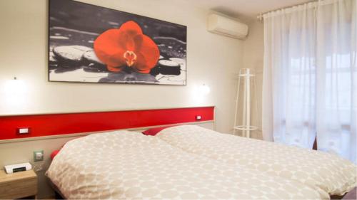 1 dormitorio con 1 cama con una flor en la pared en Le Petit Monde - Eleganza e relax in centro a Abano Terme, en Abano Terme