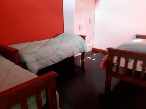 a bedroom with two beds and a red wall at Estrella del Alma in Capilla del Monte