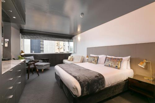 a bedroom with a large bed and a desk at The Soho Hotel in Adelaide