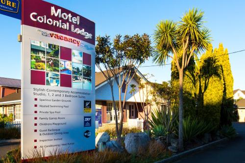 a sign in front of a house with palm trees at ASURE Colonial Lodge Motel in Napier