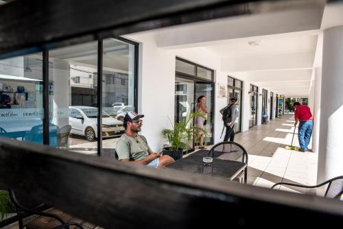 un homme assis à une table à l'extérieur d'un bâtiment dans l'établissement Hotel Plaza Playa, à Playa del Carmen
