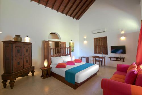 a bedroom with a bed and a tv and a couch at Amaloh Boutique Resort in Matara