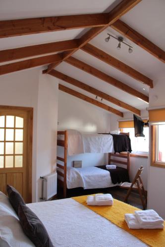 1 dormitorio con 2 camas en una habitación con techos de madera en Hostal Fernando de Magalhaes, en Punta Arenas