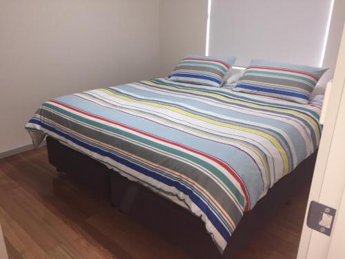 a bed with two pillows and a striped blanket at Glenaire apartments at Pontifex in Strahan