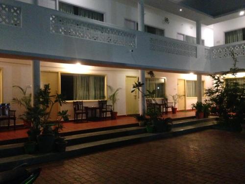 a building with a balcony and tables and chairs at Meya Beach Walk Hotel in Mahabalipuram