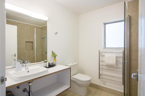 a white bathroom with a sink and a toilet at Abel Tasman Lodge in Marahau