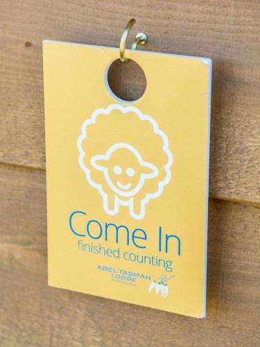 a yellow sign attached to a door with a string at Abel Tasman Lodge in Marahau