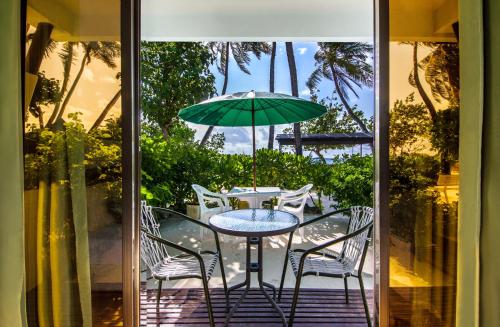 einen Tisch mit Stühlen und einem Sonnenschirm auf einer Terrasse in der Unterkunft Salt Beach Hotel in Maafushi