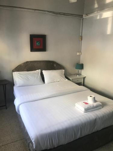 a bedroom with a large white bed with towels on it at Scandalic Bar and Guest house in Pattaya Central