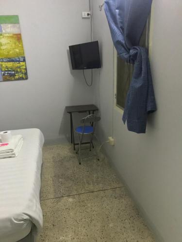 a small room with a bed and a table and a television at Scandalic Bar and Guest house in Pattaya Central