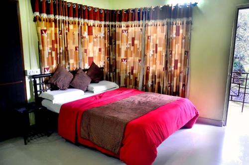 Un dormitorio con una cama con una manta roja. en Radhanand Holiday Home, en Panhāla
