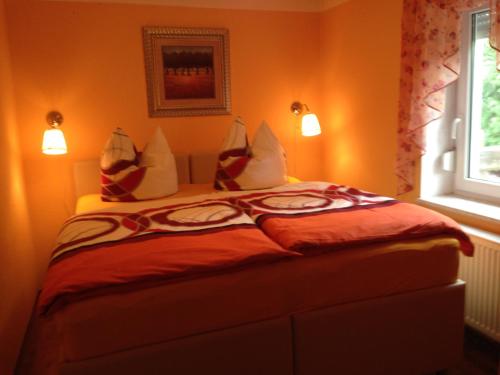 a bedroom with a bed with orange walls and a window at Ferienhaus 2 Am Eichenberg in Blankenburg