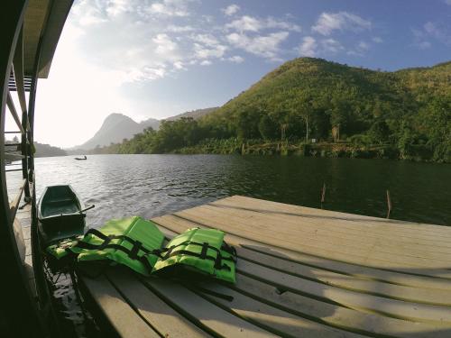 a boat on a lake with mountains in the background at Baan Krupong in Ban Tha Thong Mon