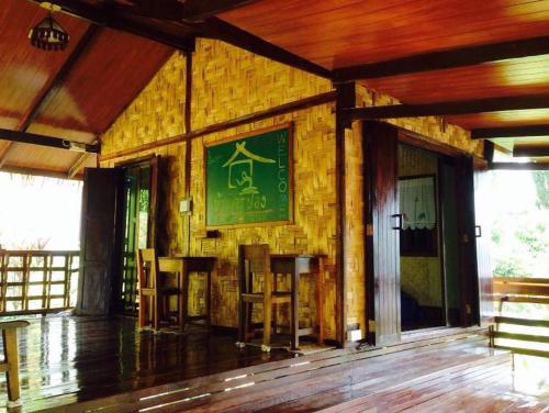 a room with a yellow brick wall with chairs and a painting at Baan Krupong in Ban Tha Thong Mon