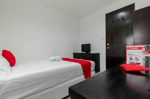 a room with a bed and a table with a red blanket at RedDoorz Plus @ Pasar Baru in Jakarta