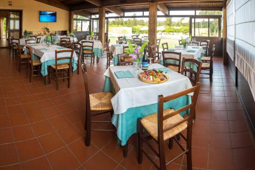 a restaurant with tables and chairs with a plate of food at Sicily Country House & Beach in Catania