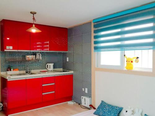 uma cozinha com armários vermelhos e uma janela em Yours Guesthouse in Tongyeong em Tongyeong