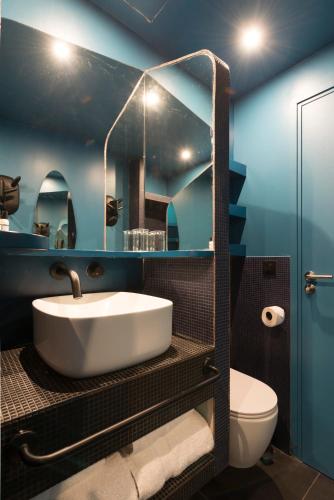 a blue bathroom with a sink and a toilet at Hôtel La Reine Jane in Hyères