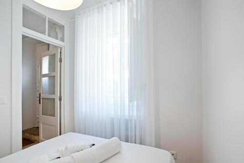 ein weißes Schlafzimmer mit einem Bett und einem Fenster in der Unterkunft BmyGuest - Ambassador Boutique Apartment I in Lissabon
