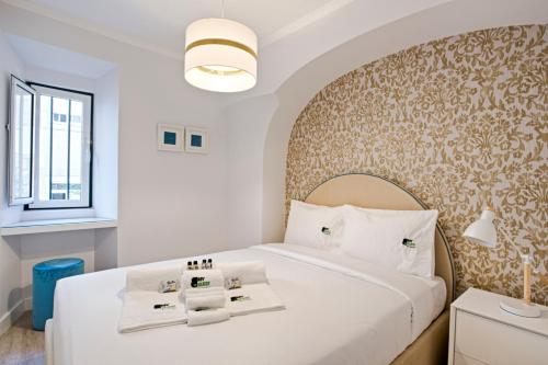 ein Schlafzimmer mit einem großen weißen Bett und einer Wand in der Unterkunft BmyGuest - Ambassador Boutique Apartment I in Lissabon