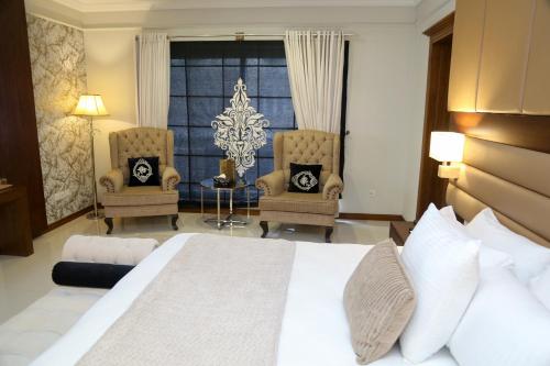 a hotel room with a bed and two chairs at Grace Boutique Hotel in Islamabad
