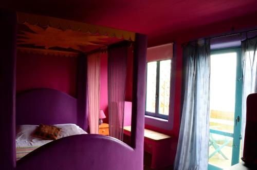 a bedroom with a canopy bed with purple walls at Hotel Alma de Romero in Carranza
