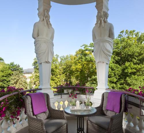 dwa posągi na ganku z krzesłami i stołem w obiekcie Imperial Spa & Kurhotel we Franciszkowych Łaźniach