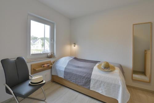 a bedroom with a bed and a chair and a mirror at Ferienhaus Ausguck in Breege
