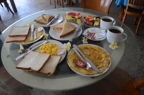 a table topped with plates of breakfast foods and coffee at Padangbai Beach Homestay in Padangbai