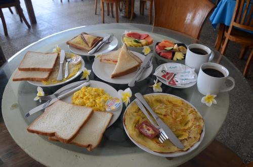 a table topped with plates of breakfast foods and coffee at Padangbai Beach Homestay in Padangbai
