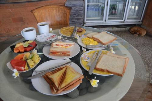 a table with plates of breakfast foods on it at Padangbai Beach Homestay in Padangbai