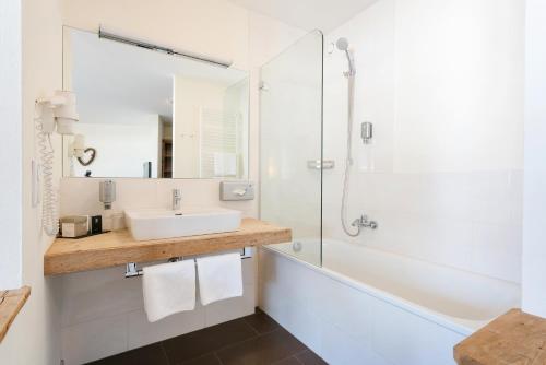 a white bathroom with a sink and a shower at Hotel Saliter Hof in Saalfelden am Steinernen Meer