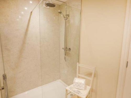 eine Dusche mit einer Glastür und einem Stuhl im Bad in der Unterkunft Brooksides Byre Durham Country Cottage in Durham