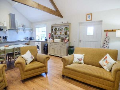 ein Wohnzimmer mit 2 Sofas und einer Küche in der Unterkunft Brooksides Byre Durham Country Cottage in Durham