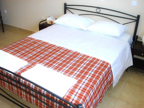 a bed with a red and white blanket on it at Dorana Apartments & Trekking Hotel in Diafani