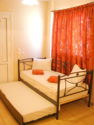 a bedroom with two beds with orange curtains at Dorana Apartments & Trekking Hotel in Diafani