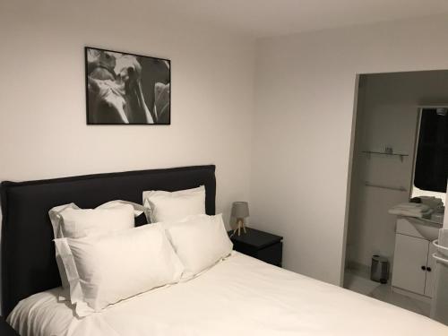 um quarto com uma cama branca e almofadas brancas em Appartements nimes em Nîmes