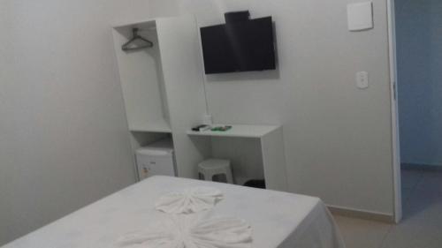 a white room with a bed and a tv at Hotel Confiança in Arapiraca