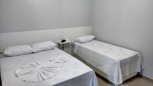 a room with two beds with white sheets at Hotel Confiança in Arapiraca