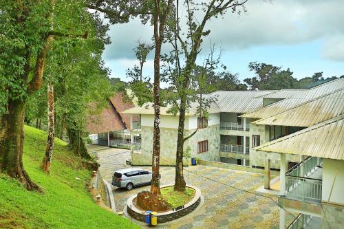 a car parked in front of a building with trees at Elixir Hills Suites Resort and Spa in Munnar
