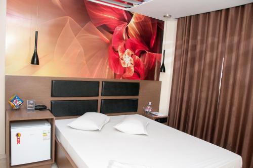 ein Schlafzimmer mit einem Bett mit einer roten Blume an der Wand in der Unterkunft Hippus Motel (Adult Only) in São Paulo