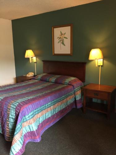 Hudson Plaza Motel Bayonne Jersey City في مدينة جيرسي: غرفة فندقية بها سرير وطاولتين ليليتين